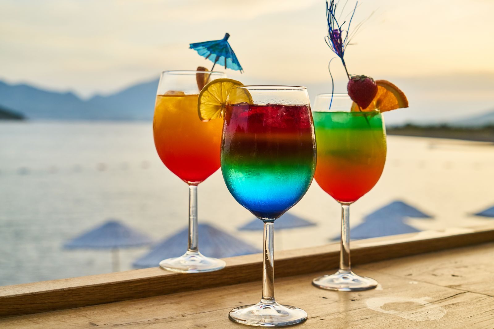Colorful cocktails lined up on a bar at sunset by the beach