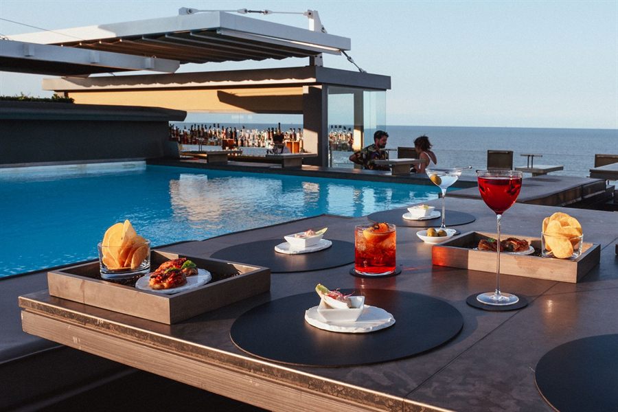 Poolside table with cocktails and snacks overlooking the sea