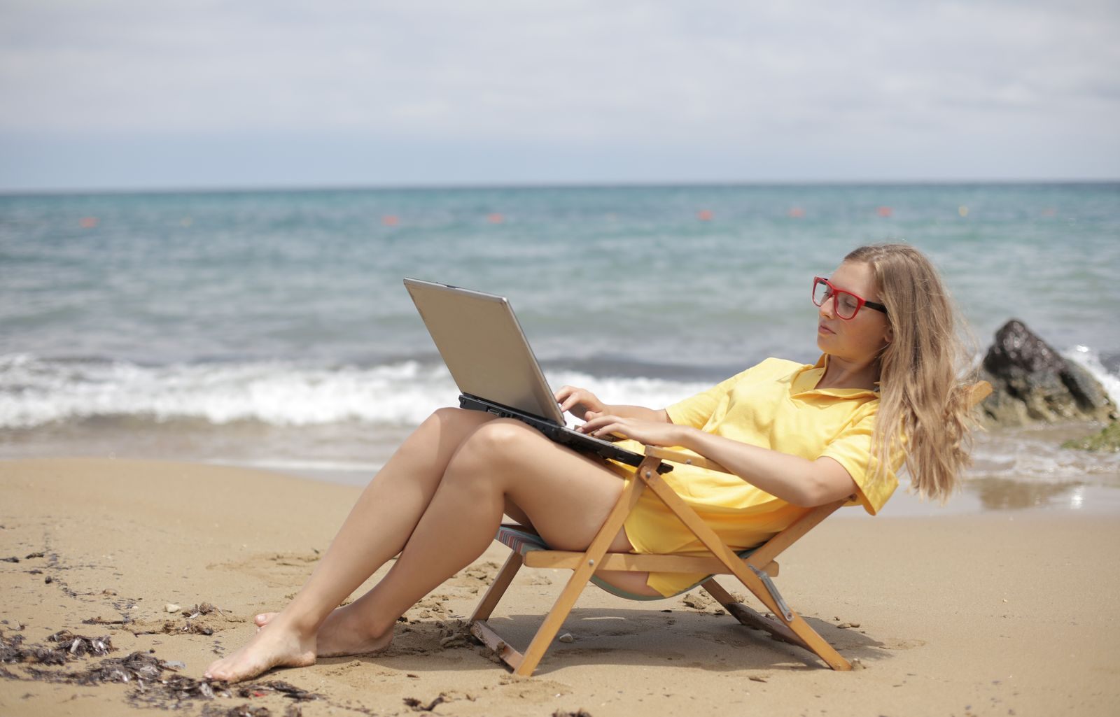 Woman using a laptop on a beach lounger by the sea